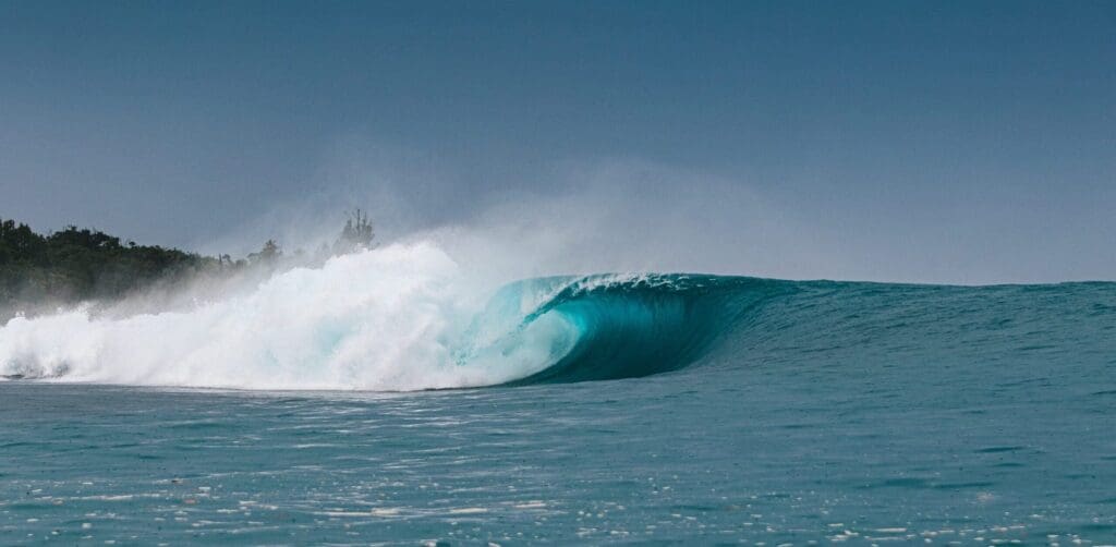 A dark blue barrel at Greenbush, Mentawai thunders along the reef infront of a stormy sky. 